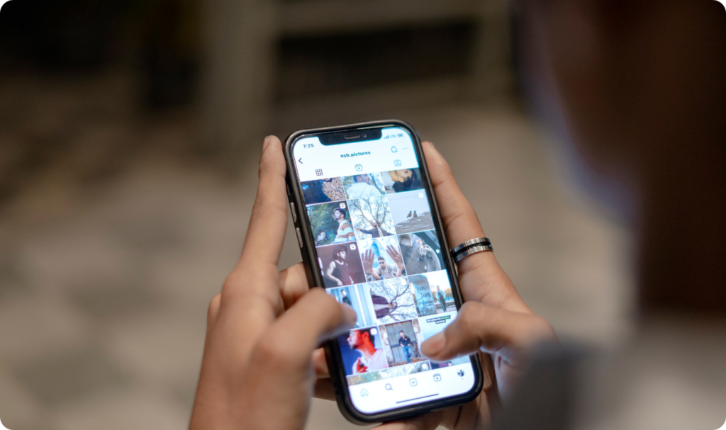 Visão em close das mãos de uma pessoa segurando um smartphone que exibe a aba 'Explorar' do Instagram, mostrando um feed de fotos e vídeos em grade, ideal para ilustrar o funcionamento do algoritmo e a descoberta de conteúdo.