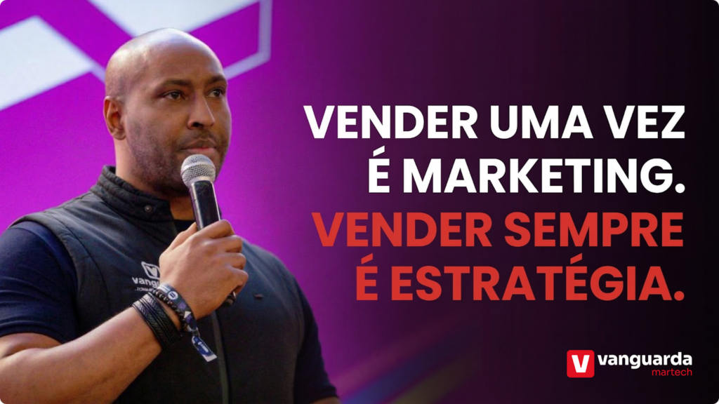Um homem negro com barba curta fala ao microfone durante uma palestra, usando um colete preto com o logo da Vanguarda Martech. Ao lado dele, um texto em letras grandes e cores contrastantes (branco e vermelho) sobre um fundo roxo diz: "VENDER UMA VEZ É MARKETING. VENDER SEMPRE É ESTRATÉGIA". No canto inferior direito, destaca-se o logotipo da Vanguarda Martech.