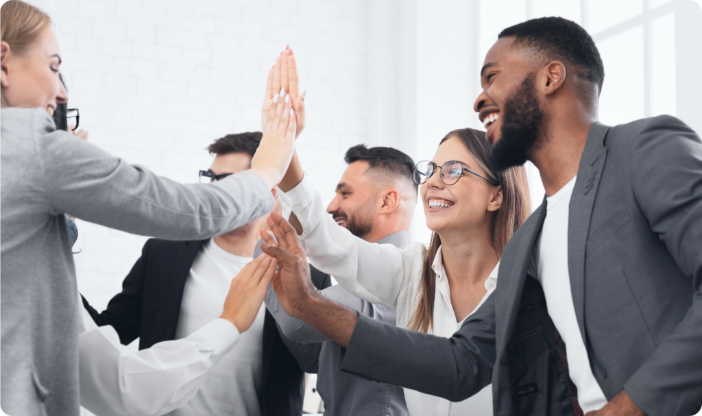 Equipe de profissionais de marketing em um escritório moderno celebrando com um 'high five' coletivo, sorridentes, simbolizando o sucesso de uma estratégia martech e o alcance de metas de performance e engajamento.